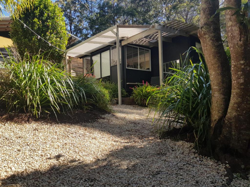 uma casa com uma árvore e plantas em frente em Forest view bungalow em Nambucca Heads