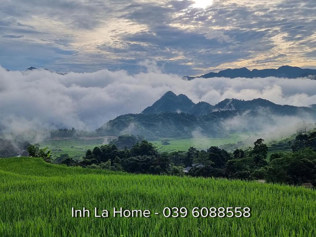 um campo verde com nuvens e montanhas ao fundo em Inh La Home Pu Luong em Pu Luong