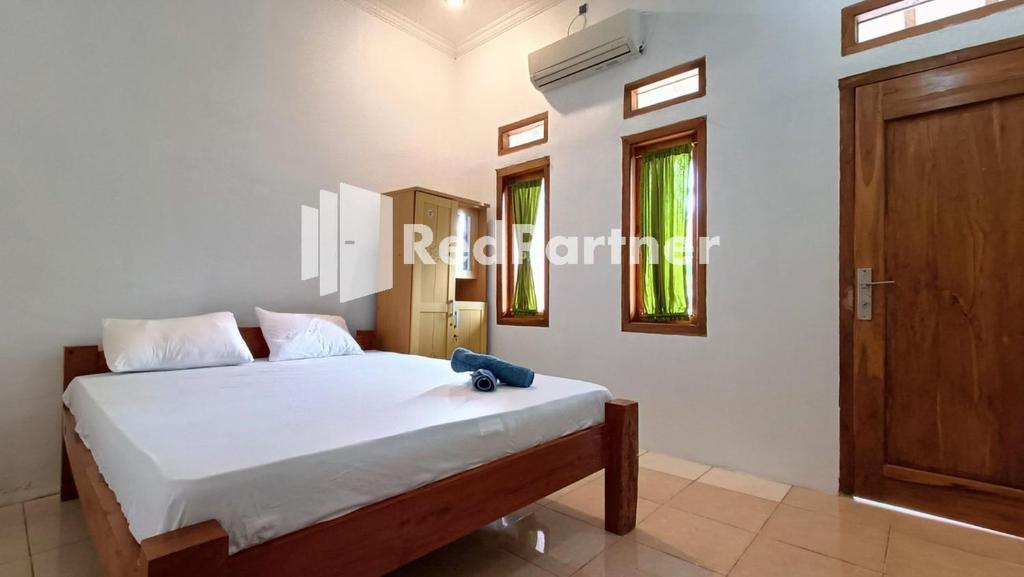 1 dormitorio con 1 cama y puerta de madera en Jogo Segoro Homestay Mitra RedDoorz near Pantai Sundak Gunungkidul, en Ngandong