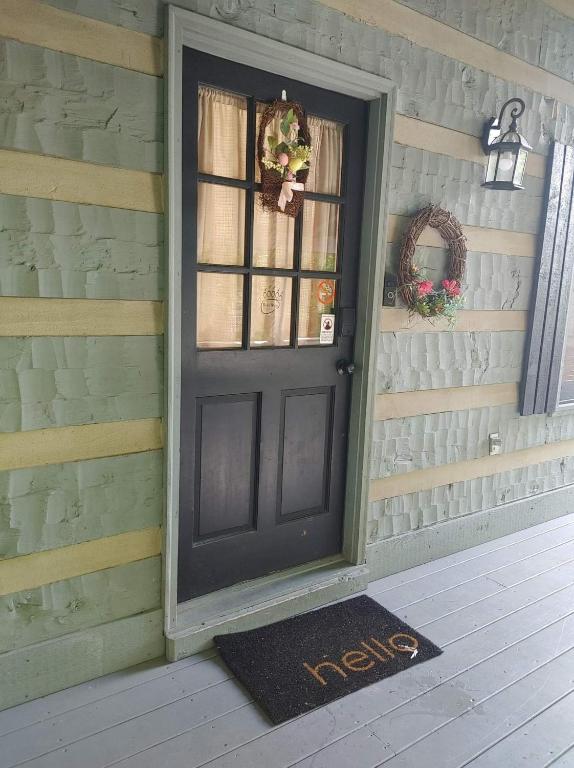 eine Tür mit einer Willkommensmatte vor einem Haus in der Unterkunft Barenberg Cabin - Secluded Unobstructed Panoramic Smoky Mountains View with Two Master Suites, Loft Game Room, and Hot Tub in Gatlinburg