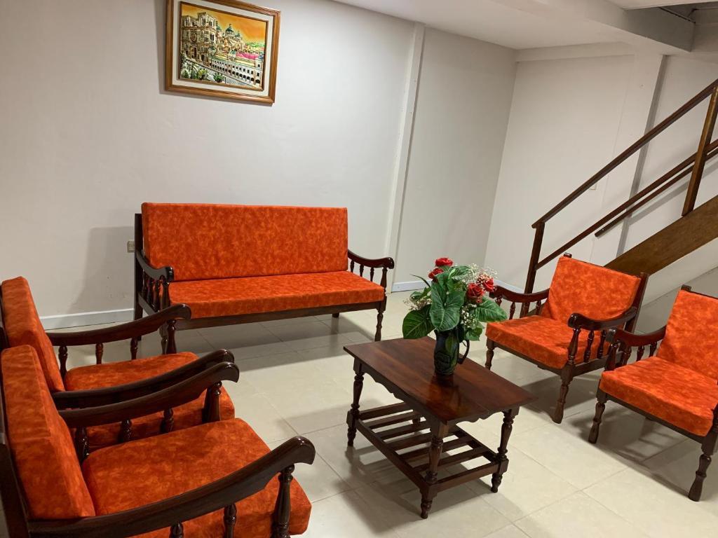 MacasにあるMy House in Macas Penhouseのオレンジの椅子と花瓶付きのテーブルが備わる客室です。