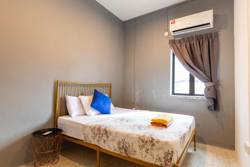 ein Schlafzimmer mit einem Bett mit blauen Kissen und einem Fenster in der Unterkunft Mac Inn 94 in George Town