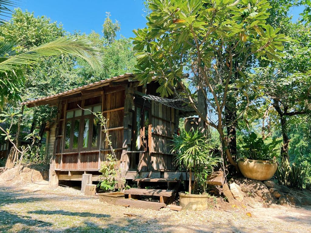 uma pequena casa de madeira com uma árvore em frente em Sukhothai City Resort em Sukhothai