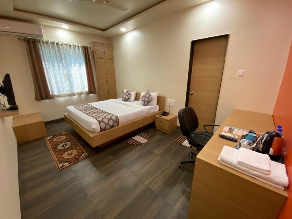 a hotel room with a bed and a desk and a desk at WOWstops VENUS in Pune