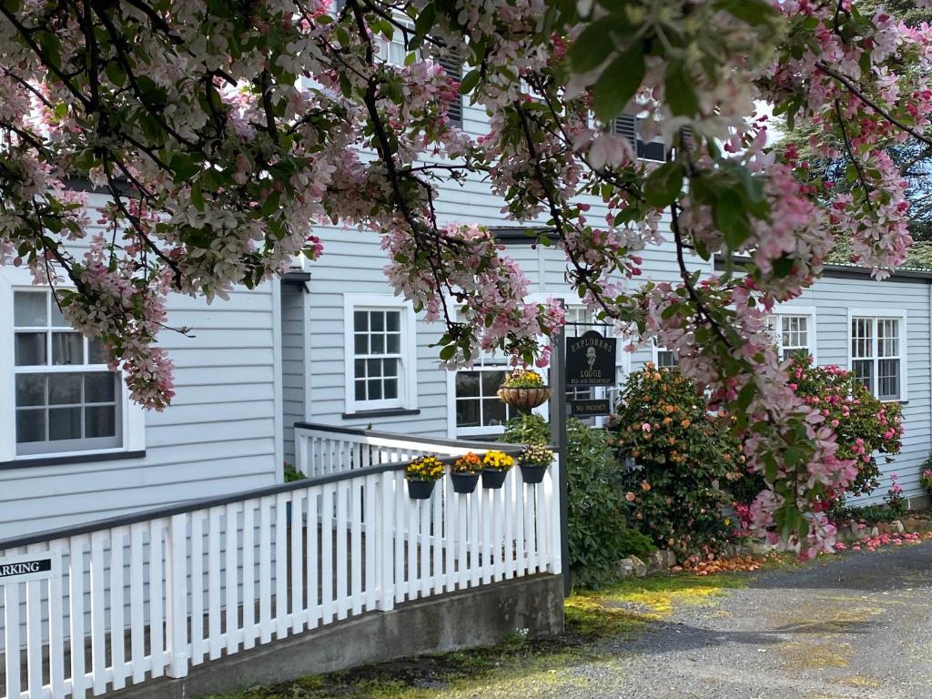 a white house with flowers on a fence at Explorers Lodge in New Norfolk