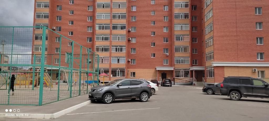 two cars parked in a parking lot in front of a building at ЖК ПРЕСТИЖ 1 комнатная квартира in Kokshetau