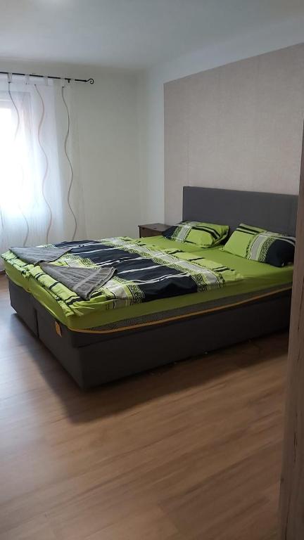 a bed with green sheets and pillows on a wooden floor at Apartment am Schlosspark 3 in Cheb