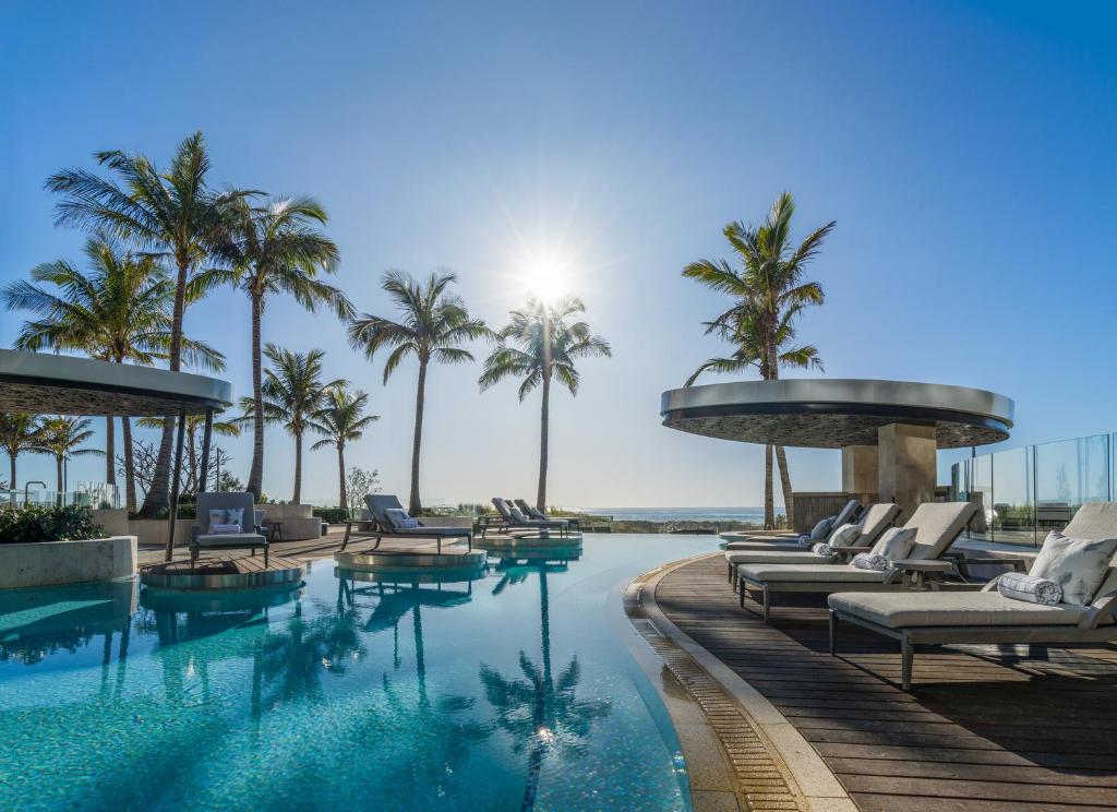 einen Pool mit Liegestühlen und Palmen in der Unterkunft The Langham, Gold Coast and Jewel Residences in Gold Coast