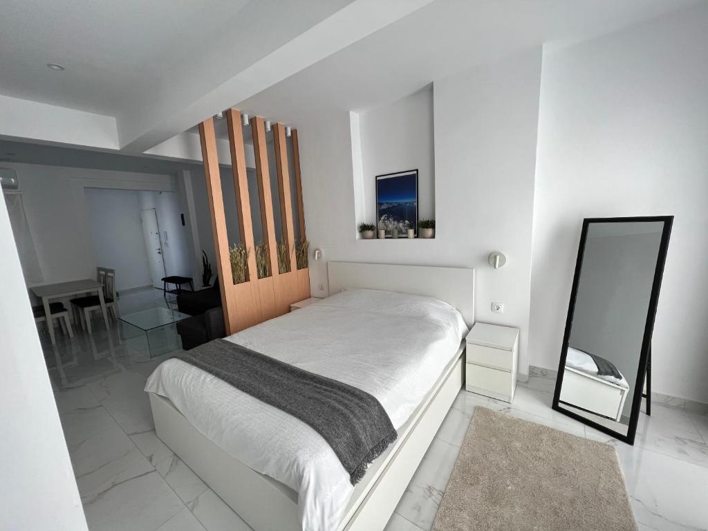 biała sypialnia z łóżkiem i lustrem w obiekcie Modern 1-bedroom apartment in the city center w Salonikach