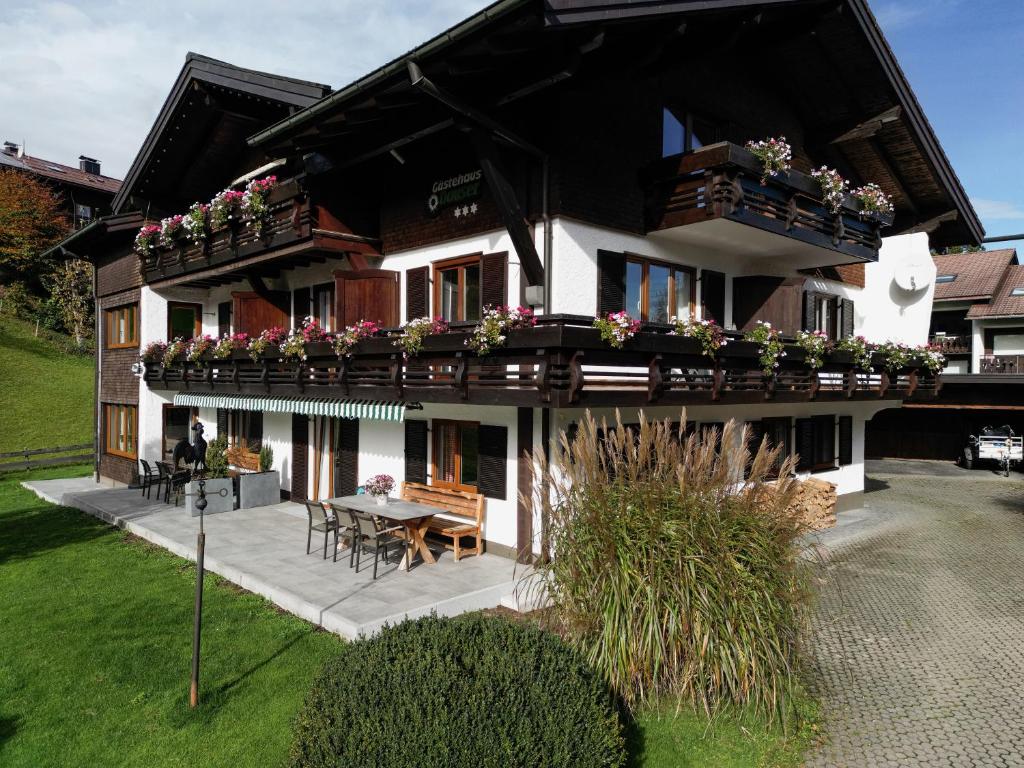 ein Haus mit Blumenkästen und einem Tisch davor in der Unterkunft Gästehaus Dauser in Obermaiselstein