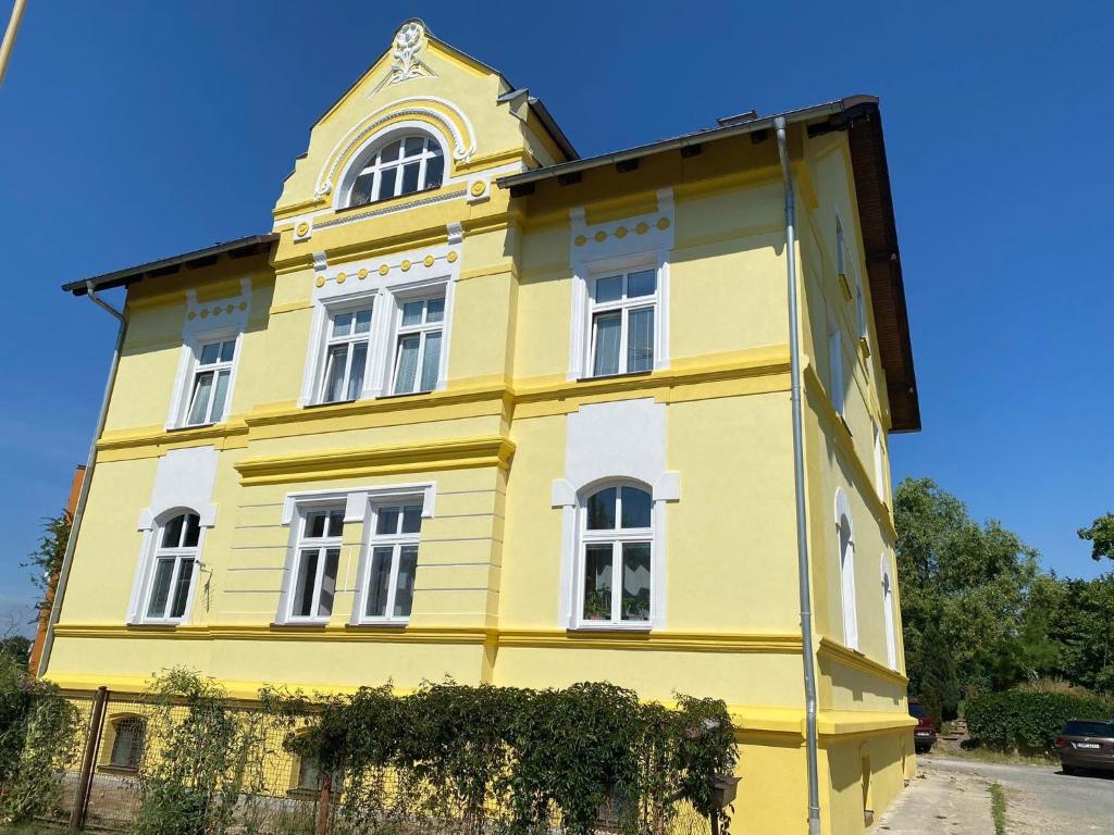 un edificio giallo con una torre sopra di VILA GALA ubytování apartmány v secesní vile Máchův kraj a Česká Lípa