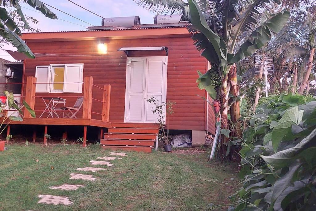 una pequeña casa roja con porche y terraza en Chalet les Azalées en Le Tampon