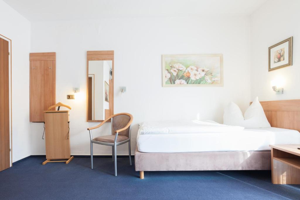 a hotel room with a bed and a chair at TM Hotel Dortmund Airport in Holzwickede