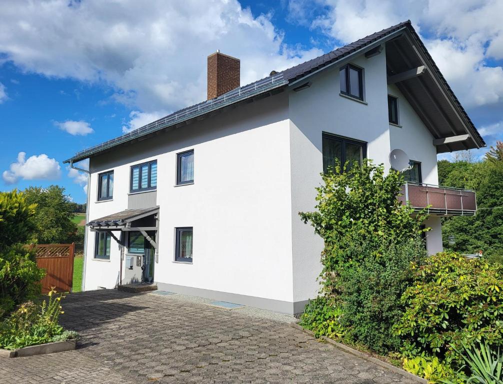 una casa blanca con techo negro en Ferienwohnung Wenzel, en Hilders