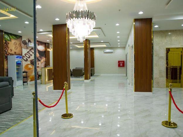 een lobby met een kroonluchter en een rood lint bij فندق روش بلس in Hafr Al Baten