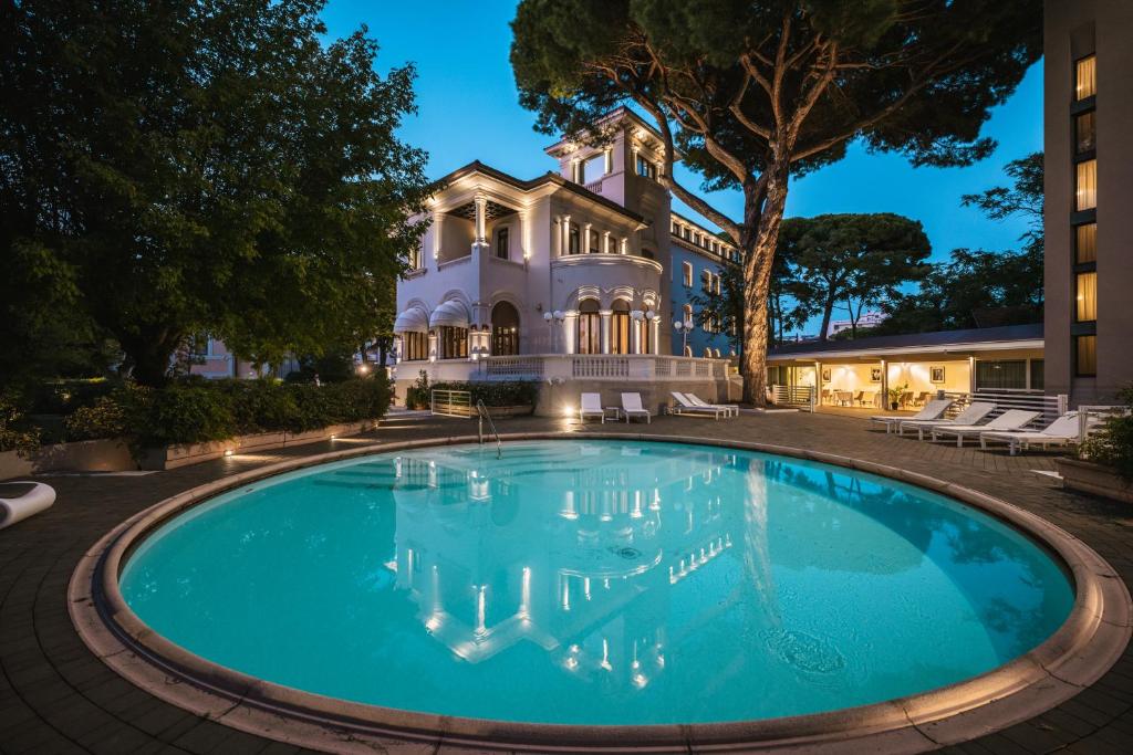 a large swimming pool in front of a building at Hotel De La Ville in Riccione