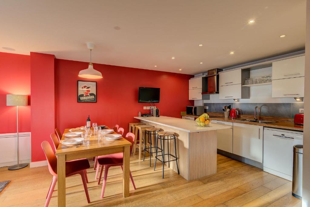 une cuisine avec des murs rouges et une table et des chaises dans l'établissement BIOLAY 2 - Alpes Travel - Central Chamonix - Sleeps 4-6, à Chamonix-Mont-Blanc