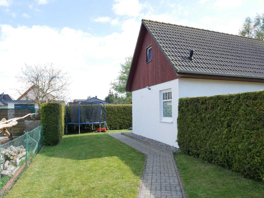 a white house with a red roof and a yard at Ferienhaus Sellin in Ostseebad Karlshagen