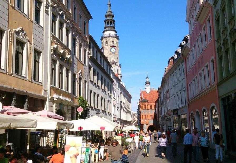 een menigte mensen die door een straat lopen met een klokkentoren bij Ferienwohnung Café Flair in Görlitz