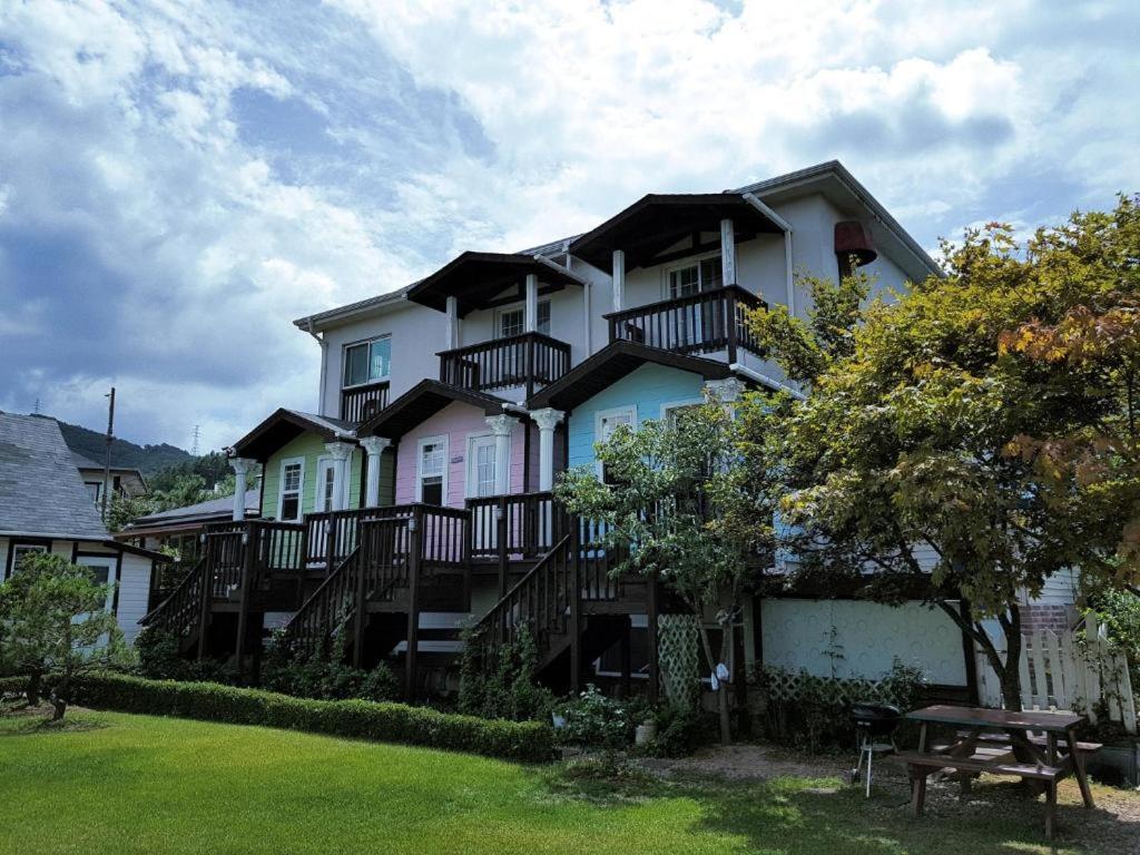 een groot wit huis met balkons en een picknicktafel bij Daegwallyeong Beautiful Pension in Pyeongchang 