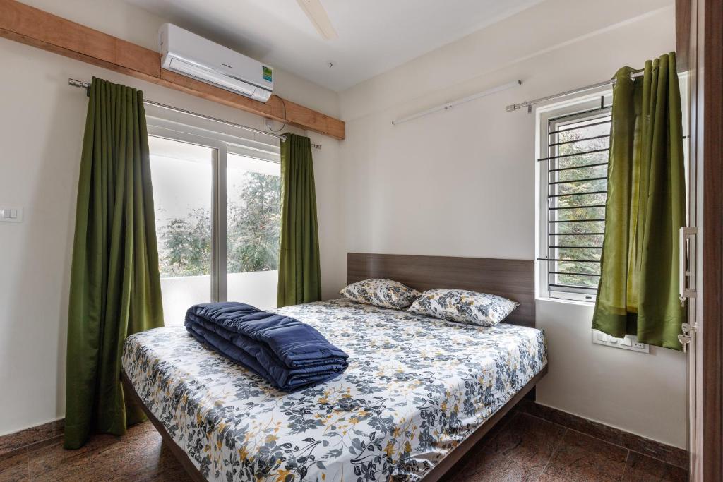a bedroom with a bed and a window with green curtains at SPLENDID SHUBHAM SERVICED APARTMENTS in Bengaluru