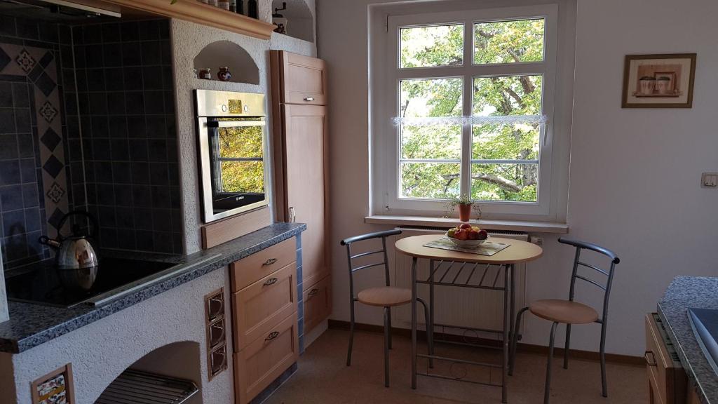 cocina con encimera, mesa y 2 ventanas en FEWO Lichtblick, en Bautzen