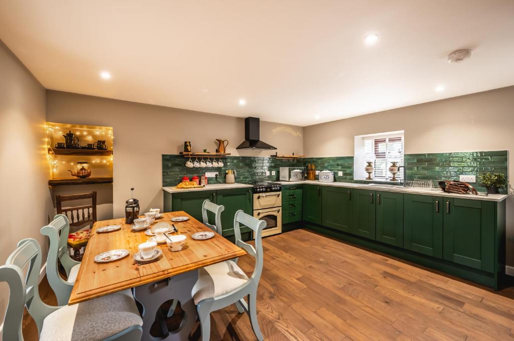 a kitchen with green cabinets and a wooden table and chairs at Luxury Cottage with Mountain View’s in Cononbridge