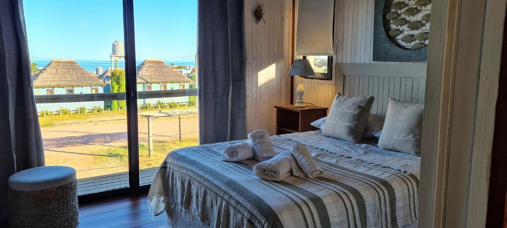 1 dormitorio con 1 cama con toallas en Cabañas 5 Sentidos, en Punta del Diablo