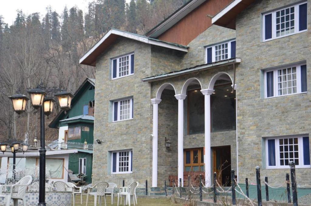 a large stone house with chairs in front of it at Hotel Outlook in Pahalgām