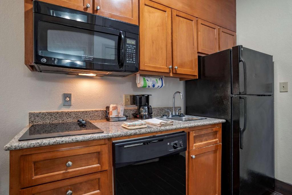 a kitchen with a black refrigerator and a microwave at MainStay Suites Denham Springs - Baton Rouge East in Denham Springs