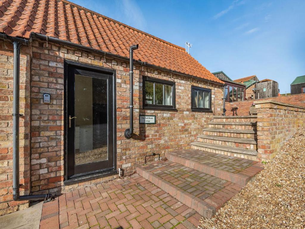 a brick house with a door and some stairs at The Tack Room - Uk36660 in Goulsby