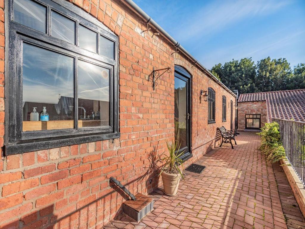 a brick building with a window and a patio at Betty Hutton - Uk36661 in Goulsby