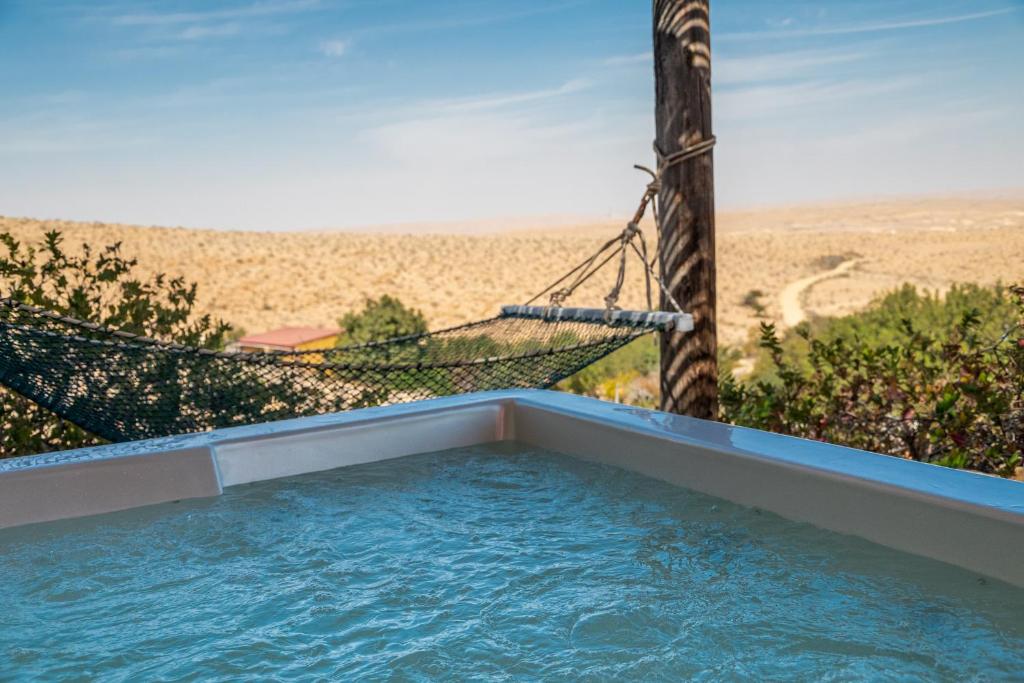 a swimming pool with a hammock and a view of the desert at Desert Estate Carmey Avdat in Midreshet Ben Gurion