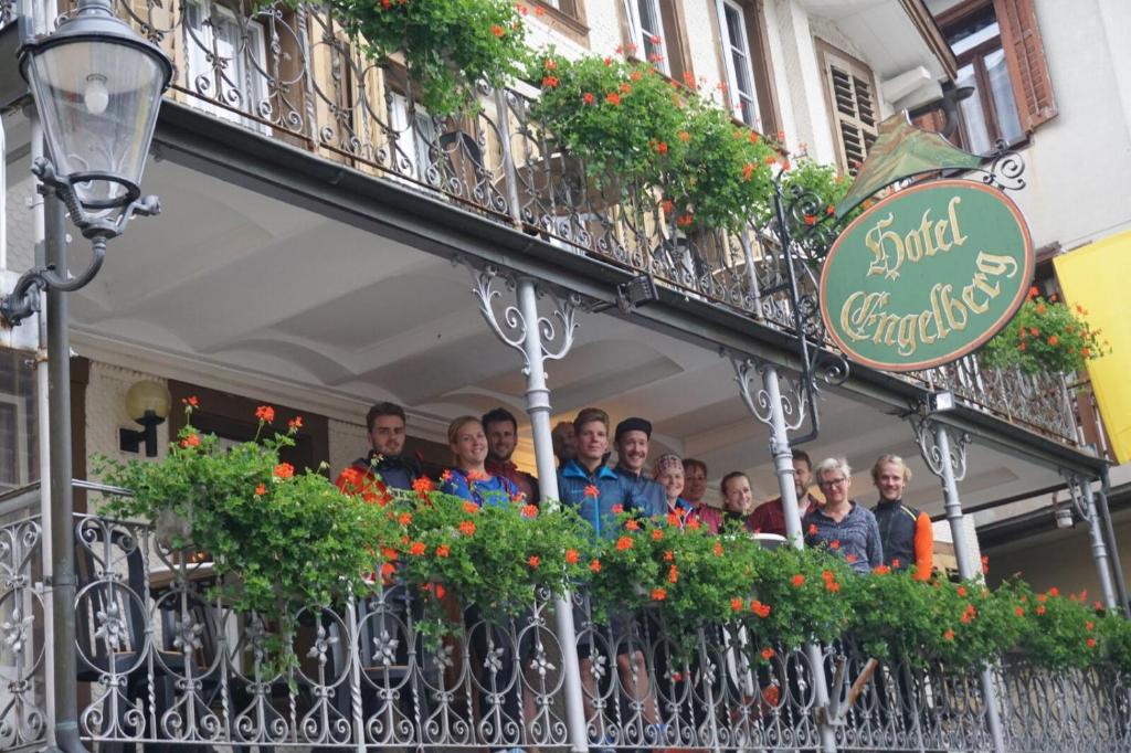 grupa osób stojących na balkonie w obiekcie Hostel Engelberg w mieście Engelberg