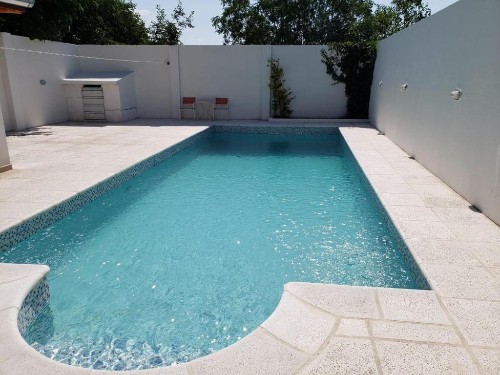 - une piscine d'eau bleue à côté d'un mur blanc dans l'établissement Hosteria Rukalaf, à Mina Clavero