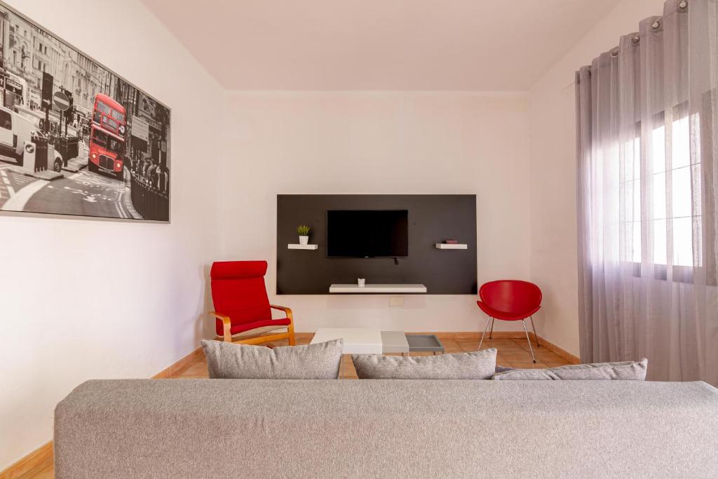sypialnia z łóżkiem, telewizorem i czerwonym krzesłem w obiekcie Los Corales w mieście El Tablero