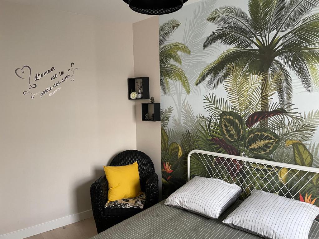 1 dormitorio con sofá y un mural de palmeras en Studio cosy avec en option piscine accessible de avril à octobre, en Quimperlé