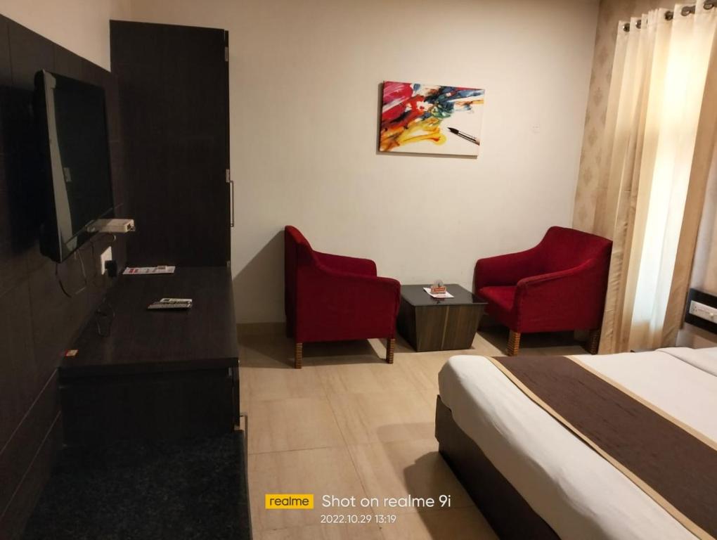 una camera d'albergo con un letto e due sedie rosse di Ashoka Hotel By WB Inn a Alwar