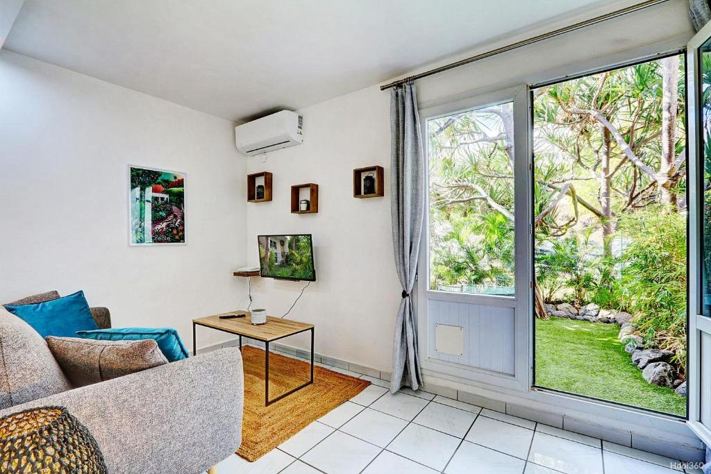 a living room with a couch and a large window at Le Vakoa - Saint Gilles les Bains in Saint-Gilles les Bains