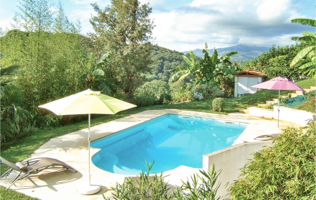 a swimming pool with an umbrella and two chairs at Lovely Home In Saint-Pée-Sur-Nivelle in Saint-Pée-sur-Nivelle