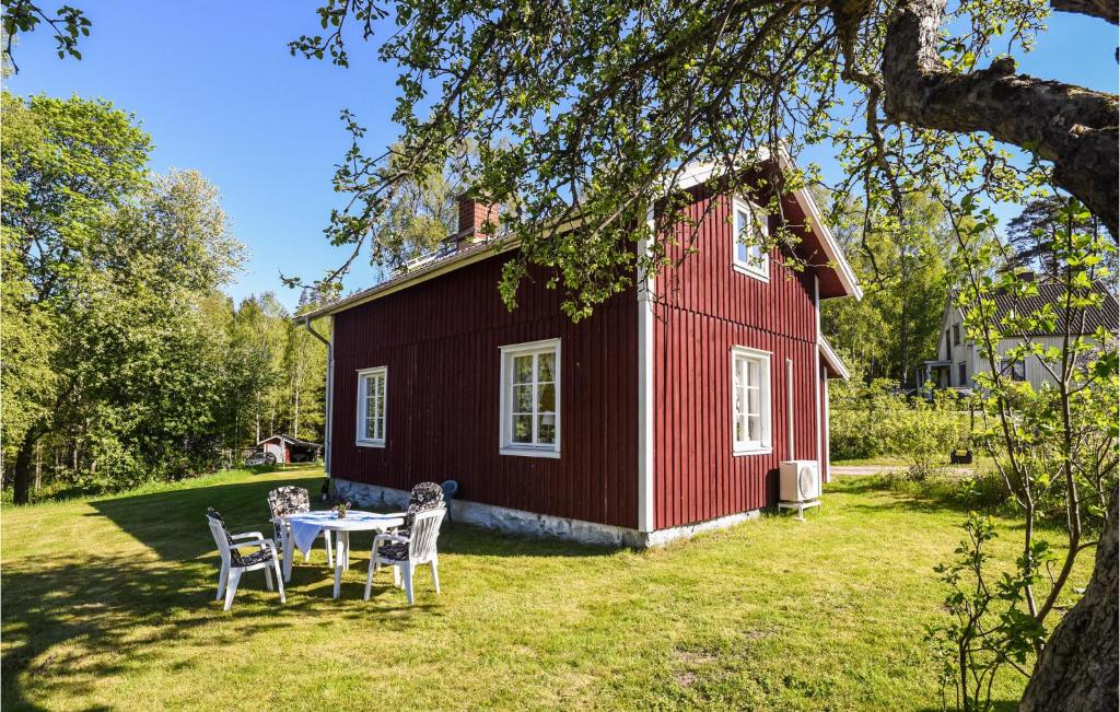 a table and chairs in front of a red barn at Nice Home In Munkedal With Lake View in Munkedal