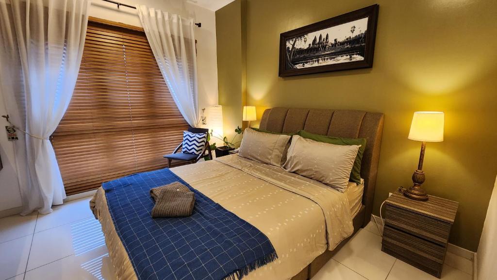 a bedroom with a bed with a blue blanket at Aldridge Residence Tropical Suite - EMIRA in Shah Alam