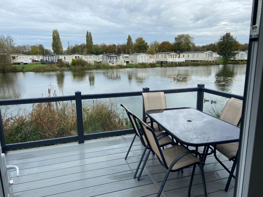 a table and chairs on a balcony with a view of a river at Sunrise - Beautiful lakeside caravan in South Cerney