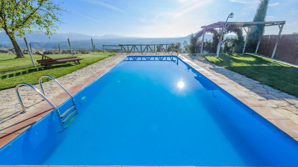 una piscina de agua azul en un patio en El Morrón Algarinejo by Ruralidays en Algarinejo