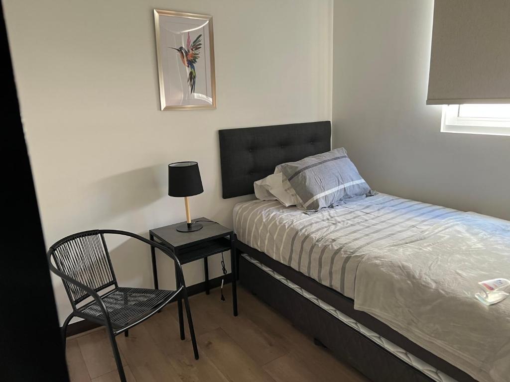 1 dormitorio pequeño con 1 cama y 1 silla en Espectacular depto Moderno 22 en Santiago