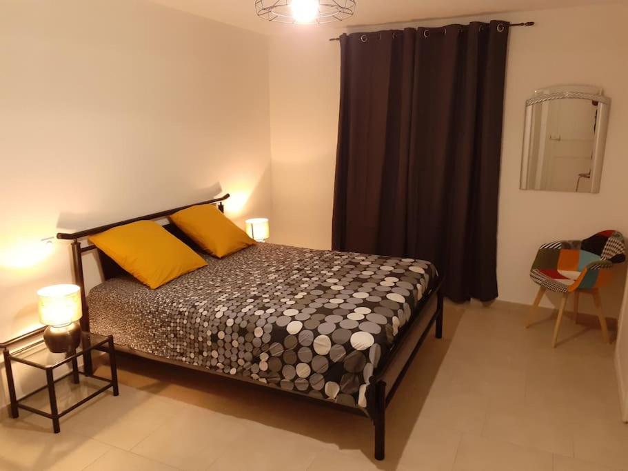 une chambre avec un lit avec des oreillers jaunes et oranges dans l'établissement L'Ancestrale, Beau T2, à Limoux