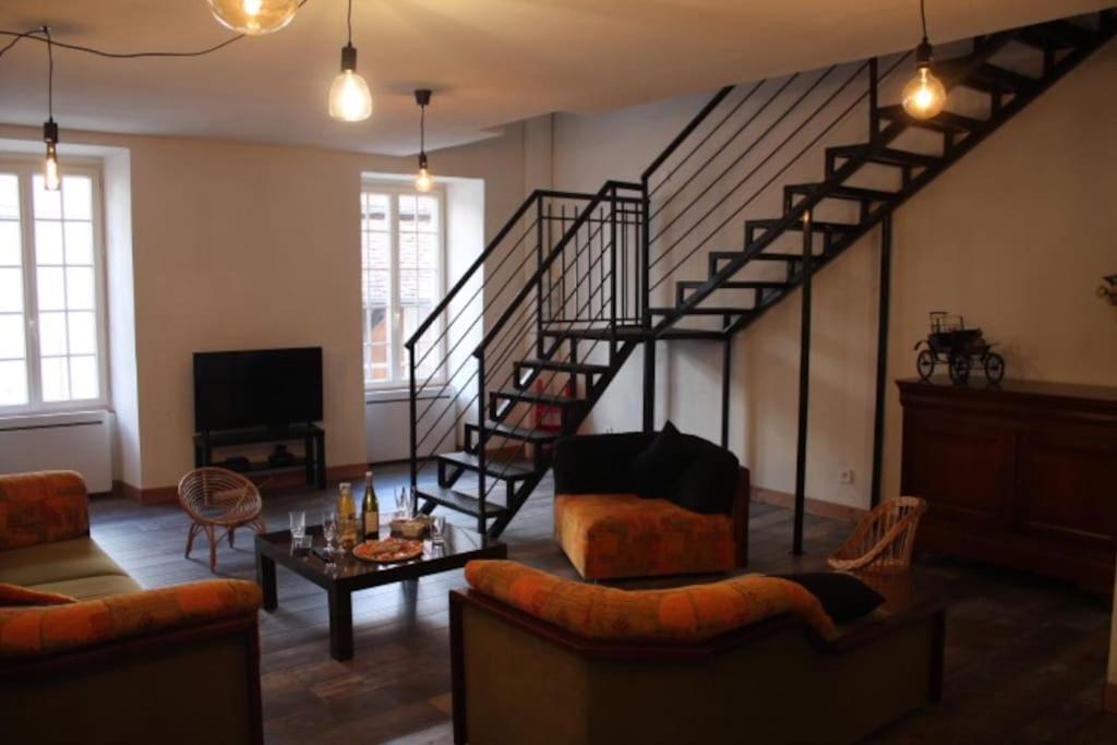 a living room with a spiral staircase and a couch at -Le Petit Mouton- Spacieux logement centre ville in Argenton-sur-Creuse