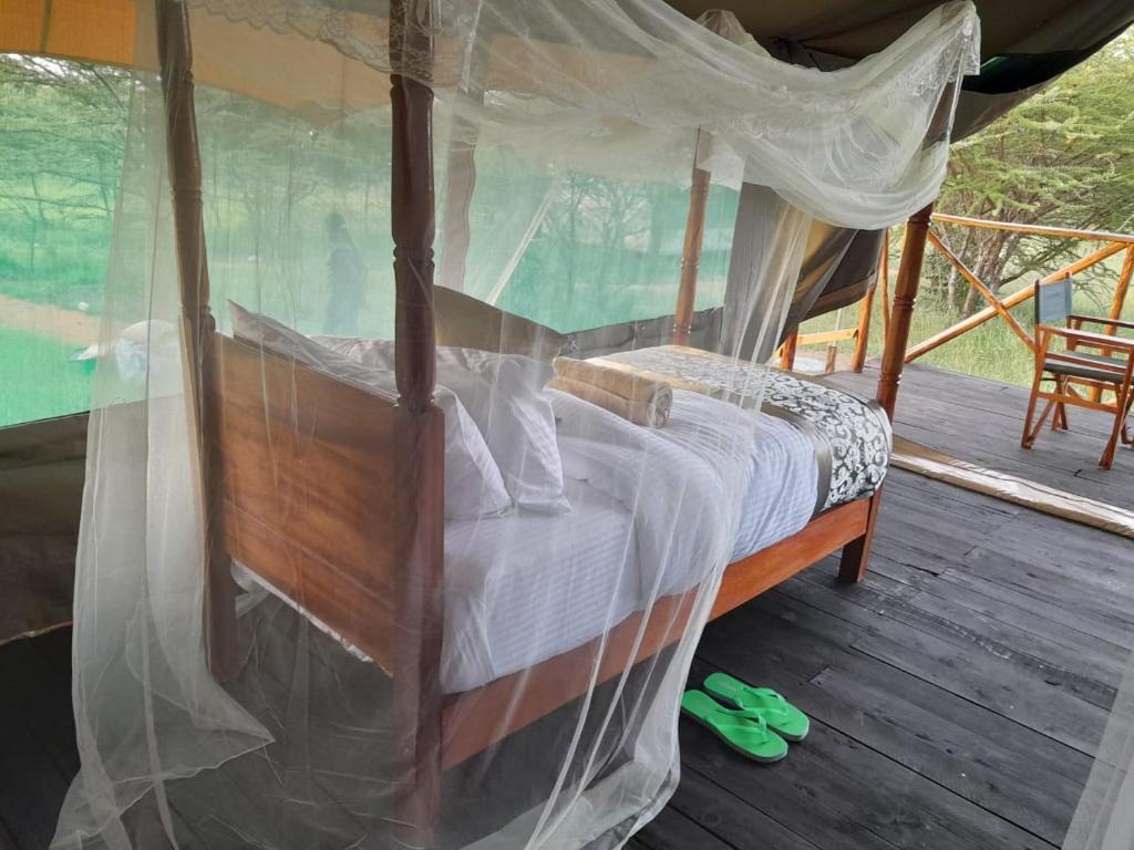 a bedroom with a canopy bed on a deck at Sonkoi Tent Safari Camp in Narok
