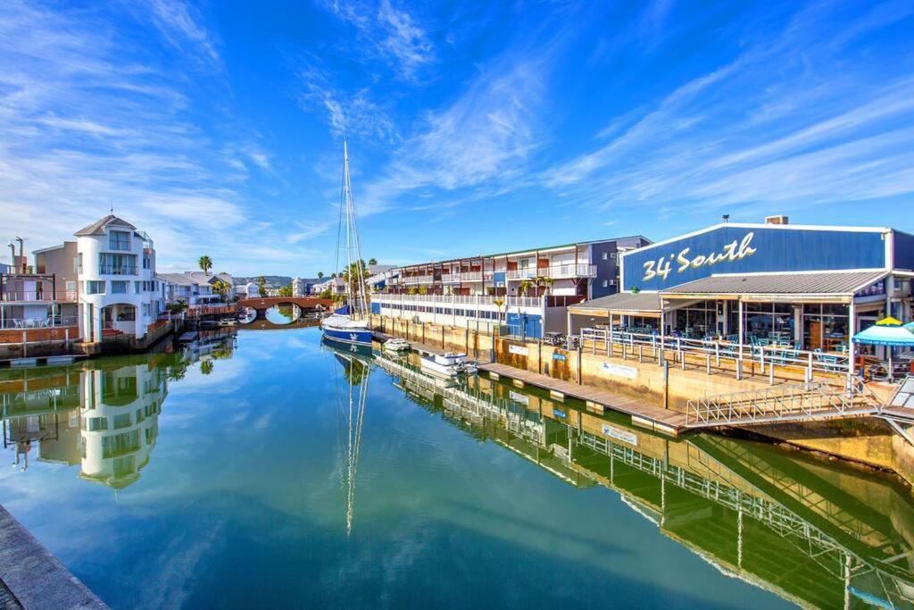 a marina with buildings and boats on the water at Sheer Nest in Knysna