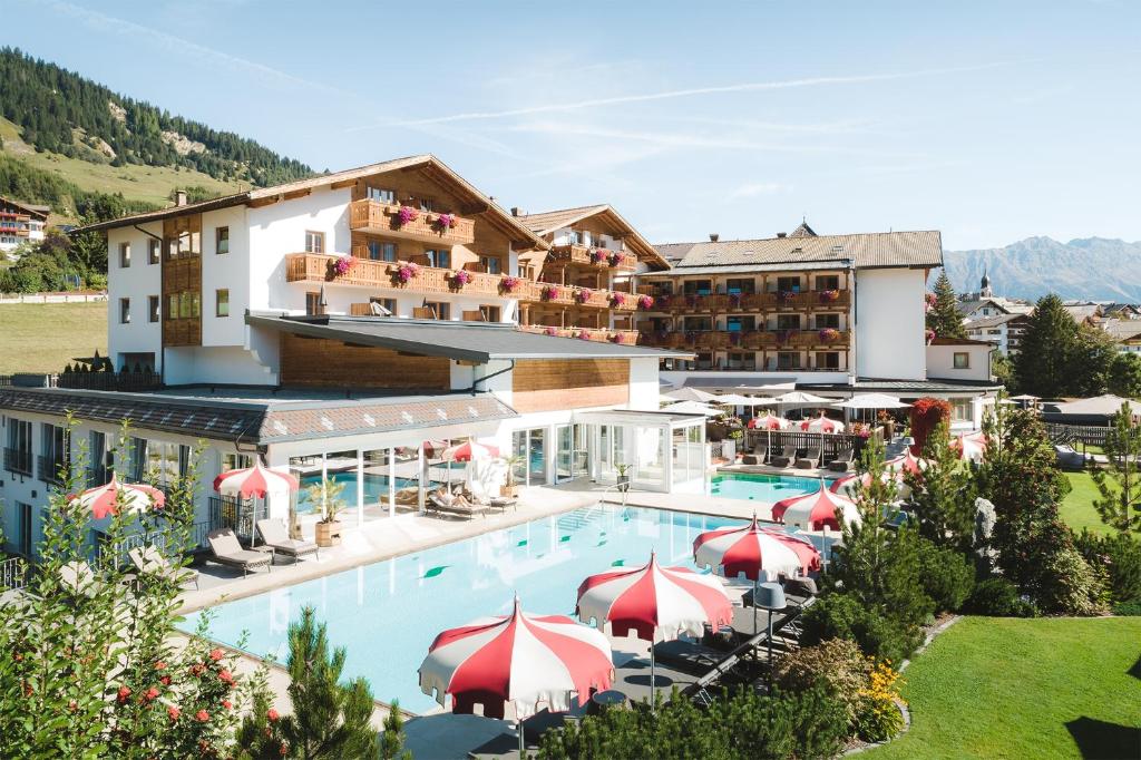 eine Luftansicht eines Hotels mit Pool und Sonnenschirmen in der Unterkunft Hotel Fisserhof in Fiss